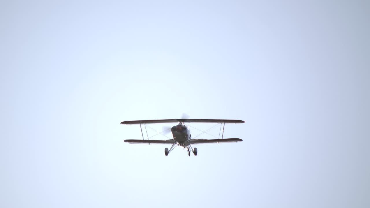Front Low Angle View of a Flying Biplane with Spinning Propeller SLOMO