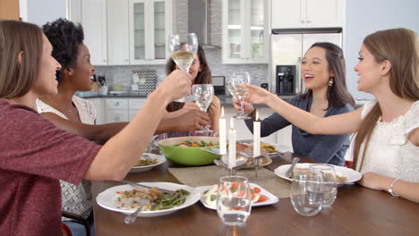 female friends make a toast and eat at a table, slow motion