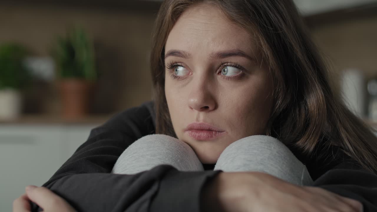 Caucasian sad woman sitting at the sofa with depression.