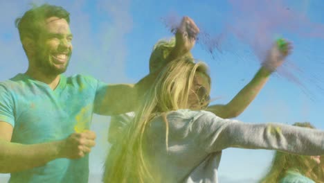 un grupo multiétnico de jóvenes diversos lanzan polvo de colores el uno al otro en la celebración del festival de holi. se divierten enormemente en este día soleado.