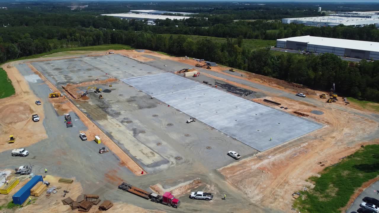 un dron orbita una plataforma de concreto mientras un camión rocía agua en el lugar de trabajo