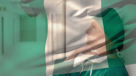 digital composition of nigeria flag waving against stressed caucasian female surgeon at hospital