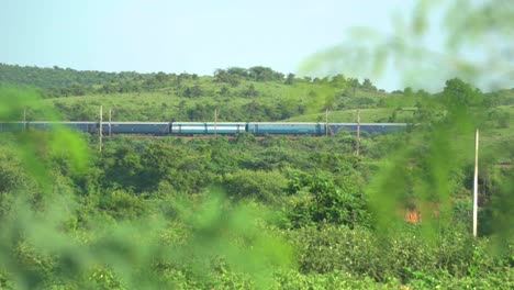 indian railways train passing through green hills in north central india