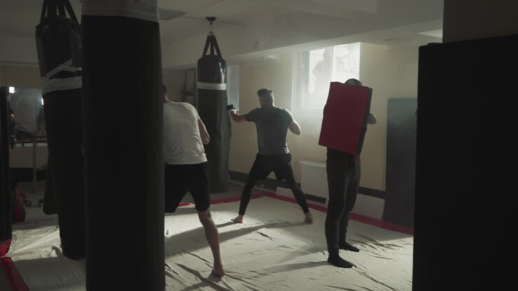 Sportsmen train hits with punching bags in sports club. Professional kickboxers team exercises in fighting gym slow motion. Healthy leisure and activity