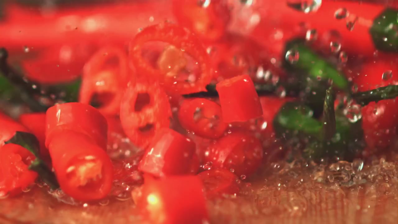 Movimento rallentato di peperoncini rossi e fette che cadono nell'acqua.