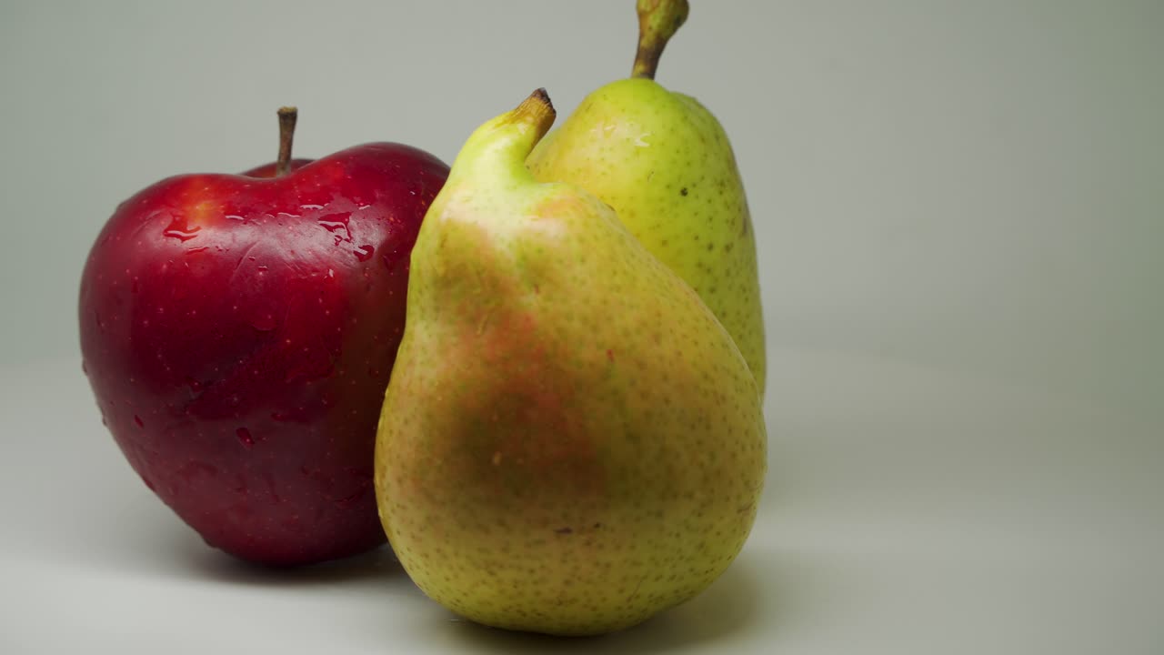 manzana roja fresca y dos hermosas peras frescas girando en el sentido de las agujas del reloj con fondo blanco puro - primer plano