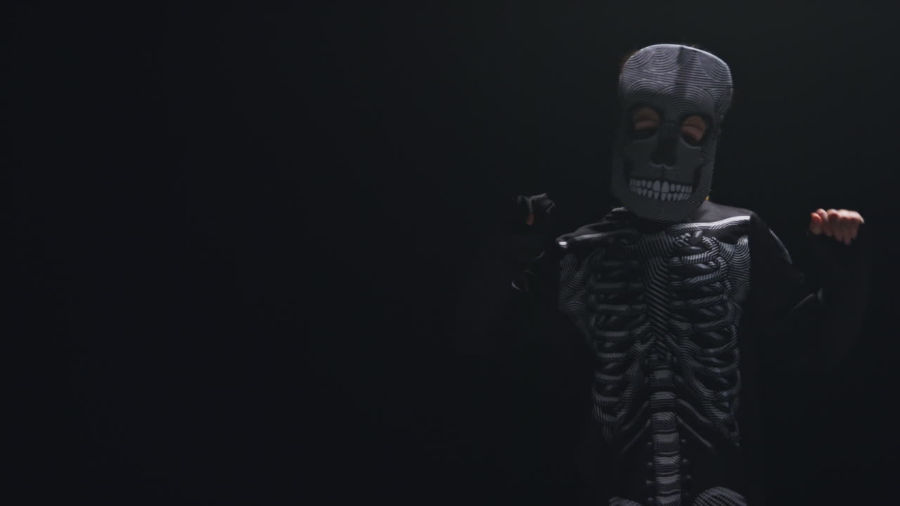 스레톤 의상을 입은 아이가 할로윈에 검은 바탕에 춤을 추는 스튜디오