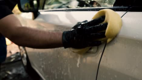 Close-up-of-a-male-washing-a-car-wearing-a-black-gloves-with-shampoo-and-sponge