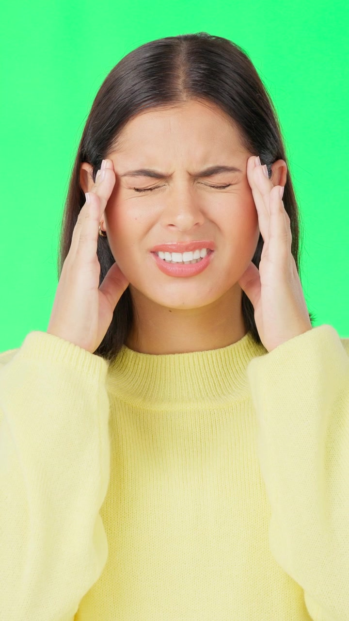 Young Woman Suffering From a Headache Against a Green Screen