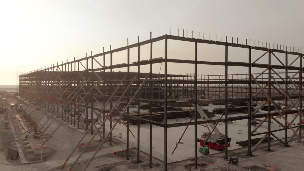 Metal warehouse structure at a construction site in a cloudy sunset