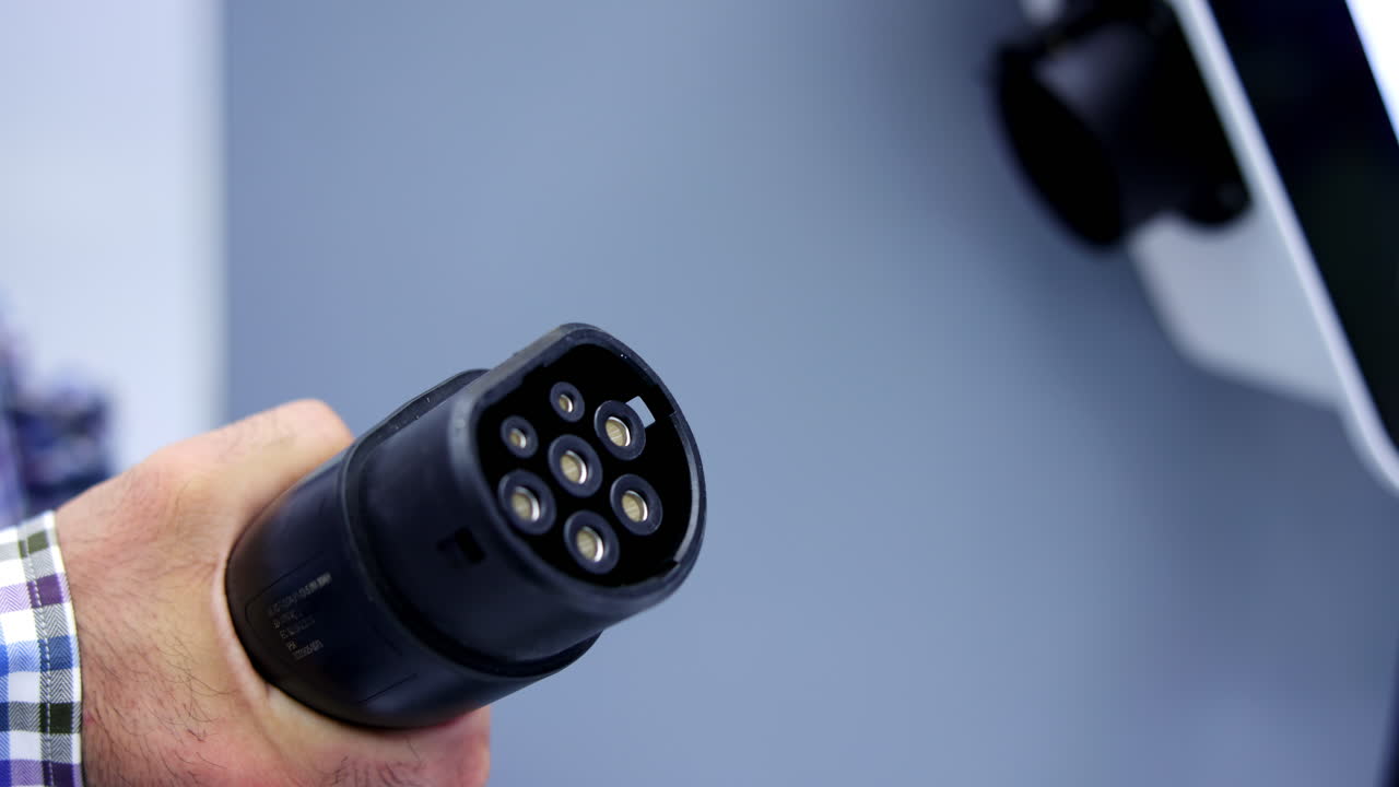 A person plugging an electric vehicle charger into a charging station
