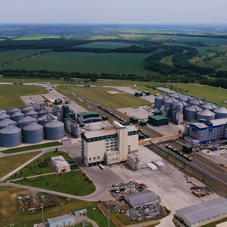 Imponente stabilimento con enormi silos e ferrovie per treni merci. Moderna zona industriale per la lavorazione dei cereali. Vista aerea. Incredibile sfondo naturale