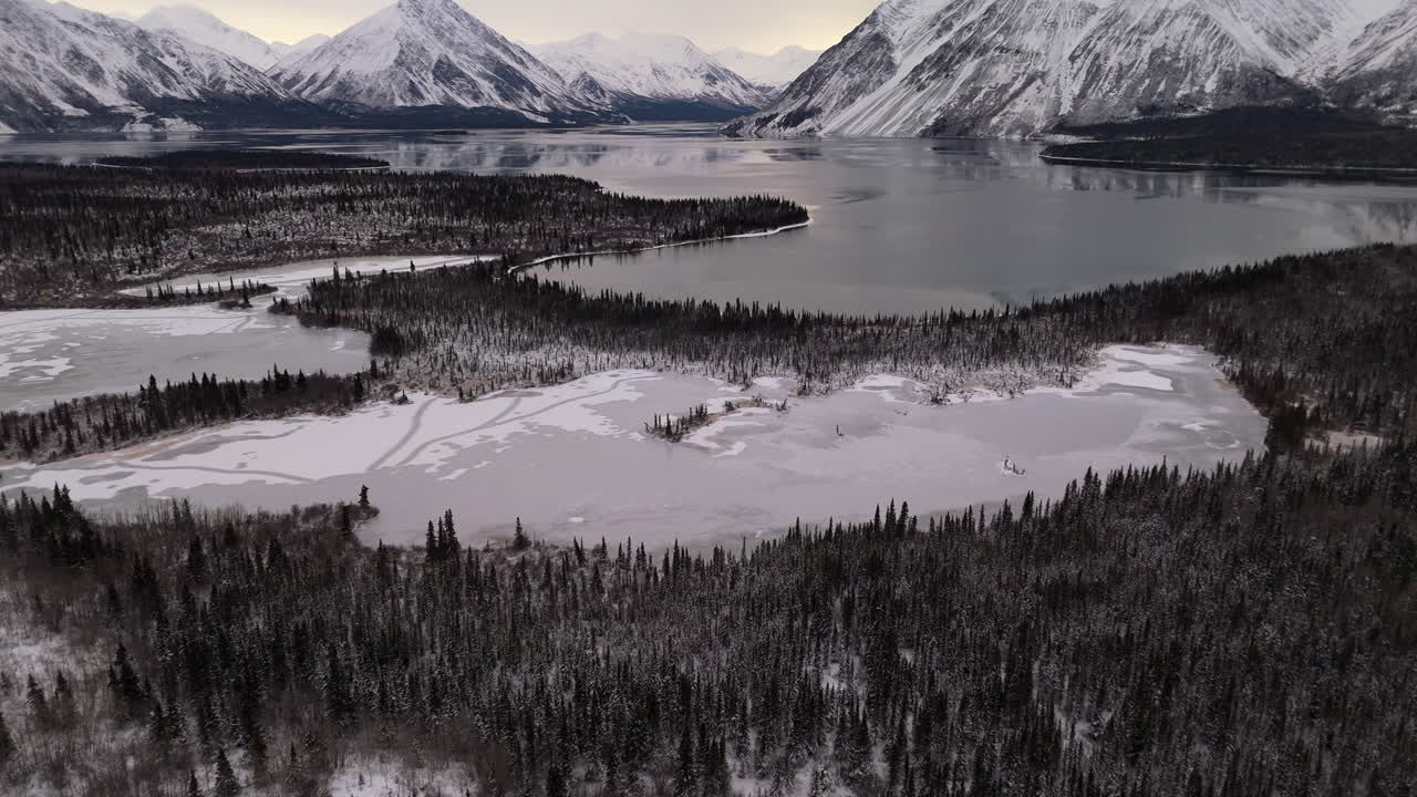Lago Kathleen congelado y bosque y montañas cubiertos de nieve en Kluane, Yukón, Canadá. - Toma aérea