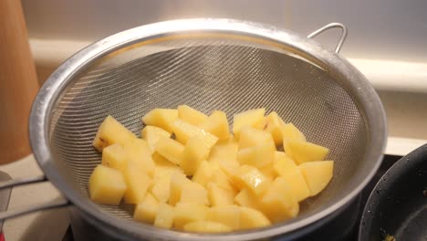 chopped peeled potatoes steaming in a pot with colander