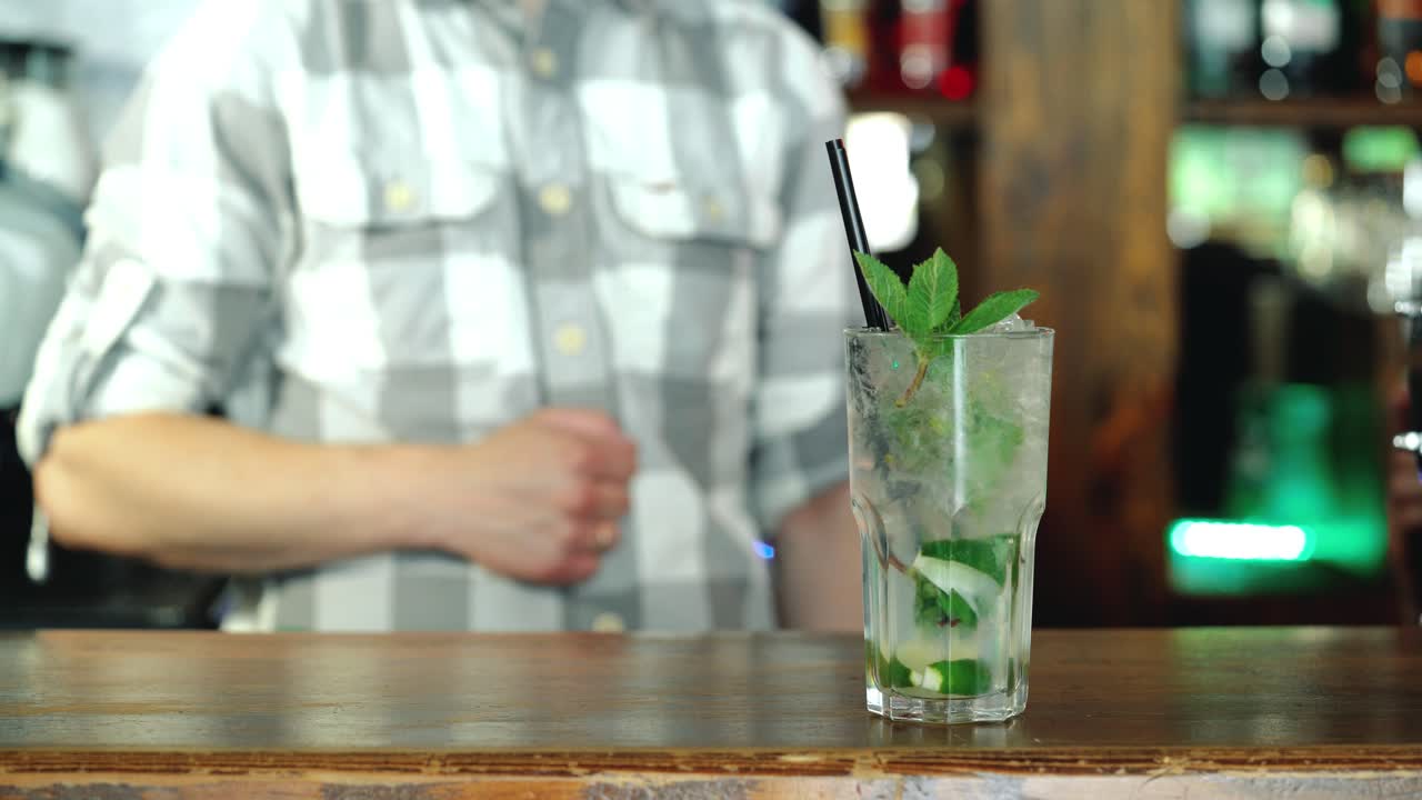 Baarimikko valmistaa raikasta, kylmää cocktailia baaritiskin päällä. Uskomaton sekoitus.
