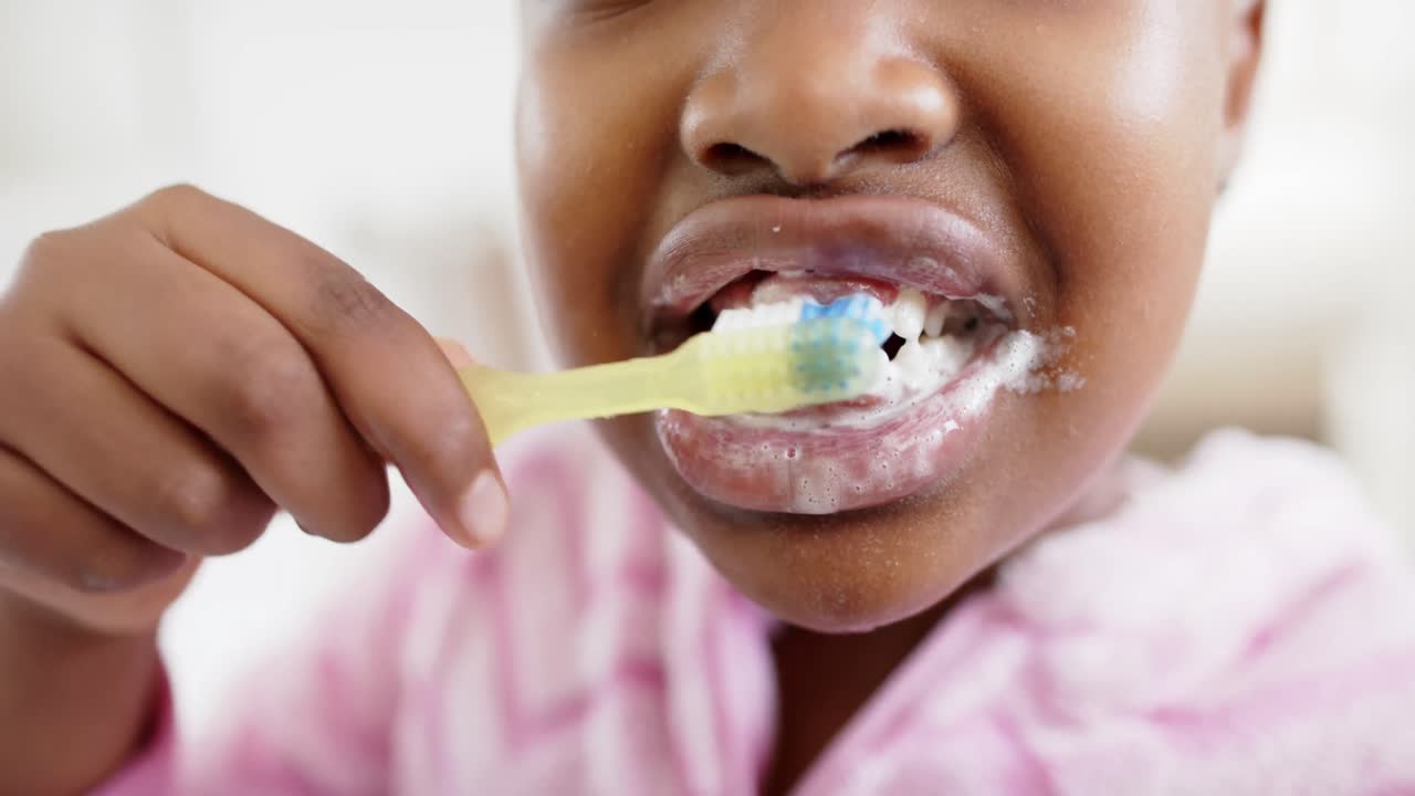 Close up of unaltered african american girl brushing teeth in bathroom, in slow motion