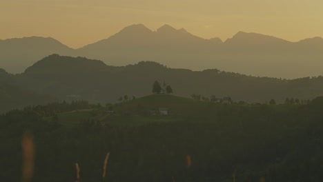 a couple with backpacks watches the sunrise over the mountains near st. thomas church, slovenia