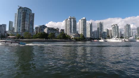 a-pair-bike-surfers,-a-water-taxi-and-a-motor-boat-passes-by-on-false-creek-yaletown-quay-right-by-the-David-Lam-Park-on-a-summer-day-with-a-reflection-on-the-water-with-parked-yachts-sunny2-3