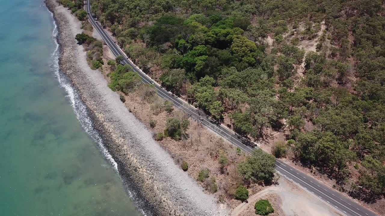 dron aéreo panorámico lento hacia arriba para revelar la montaña junto a una playa tropical y una carretera