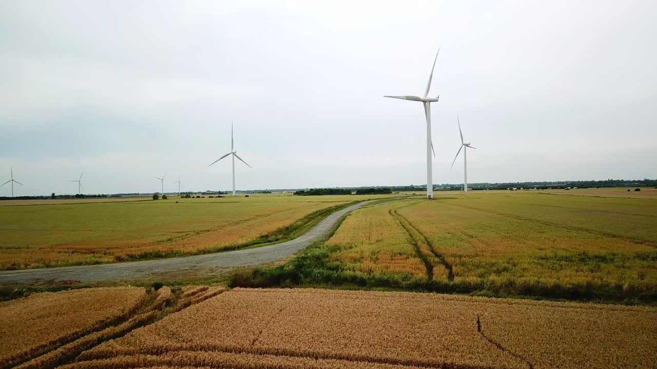 Drone shot -- Wind Turbines spinning over agricultural fields