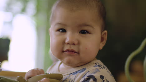 Retrato-De-Un-Adorable-Y-Lindo-Bebé-Asiático-Birracial-De-Raza-Mixta-Mira-La-Lente-De-La-Cámara-Y-Luego-Ríe-Y-Sonríe-Con-Un-Juguete