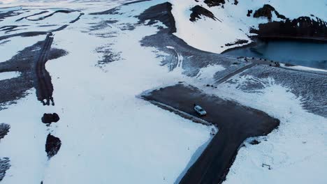 car parking on road on snowy shore of a lake in viti crater, iceland