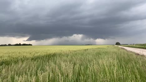 Storm-clouds-build-in-the-distance-on-a-Kansas,-country-road-with-a-lightning-strike