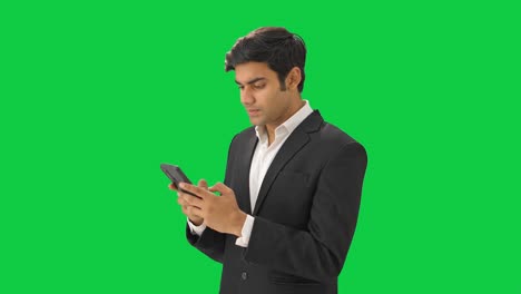 Indian-businessman-texting-on-phone-Green-screen