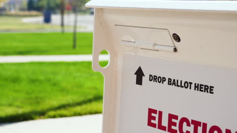 drop ballot here sign with arrow and slot for mail-in election voting box with person walking in background