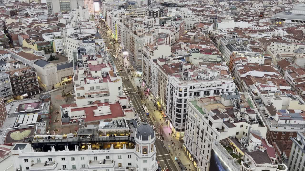 Street view of Madrid’s Gran Vía in January with people walking along the famous boulevard, cars and city lights under a cloudy winter sky, showcasing the beautiful architecture of Spain’s capital