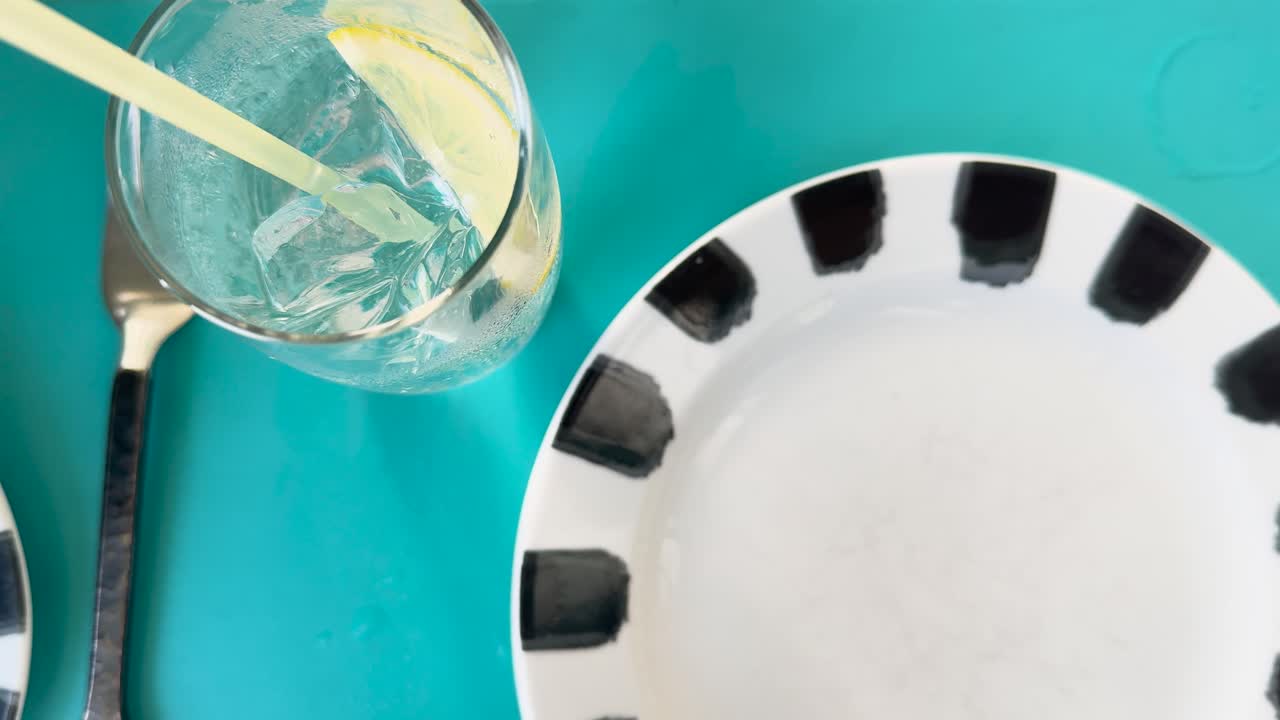 un vaso de refresco con limón y hielo en una mesa vibrante, destacando los momentos refrescantes de la cena