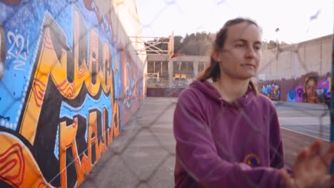 joven mujer caucásica entrando en un patio de recreo urbano adornado con graffiti vibrante