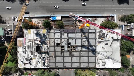 an aerial shot showing the progress of a construction site with multiple cranes lifting materials