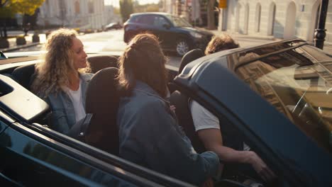 Glückliche-Freunde-In-Einem-Dunkelgrauen-Cabrio-Sind-Am-Ziel-Angekommen-Und-Parken-Ihr-Auto,-Sie-Unterhalten-Sich-Und