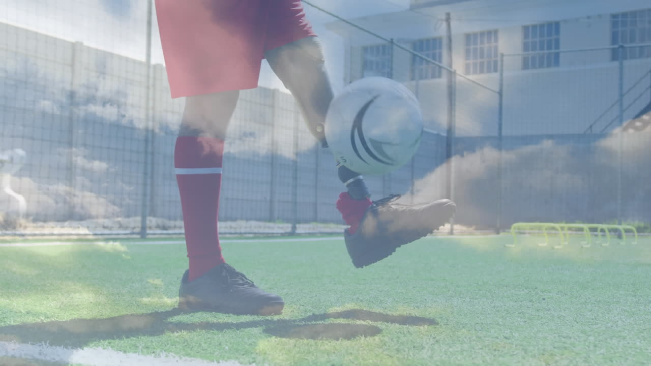 장애인 아프리카계 미국인 남자가 인공 다리를 가지고 축구를 하고 있는 구름이 있는 하늘의 애니메이션