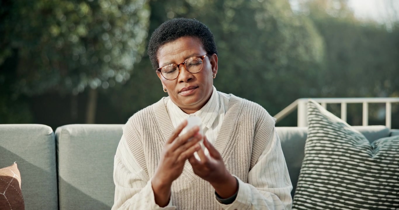 Mature Woman Examining Medication Bottle While Sitting Outdoors