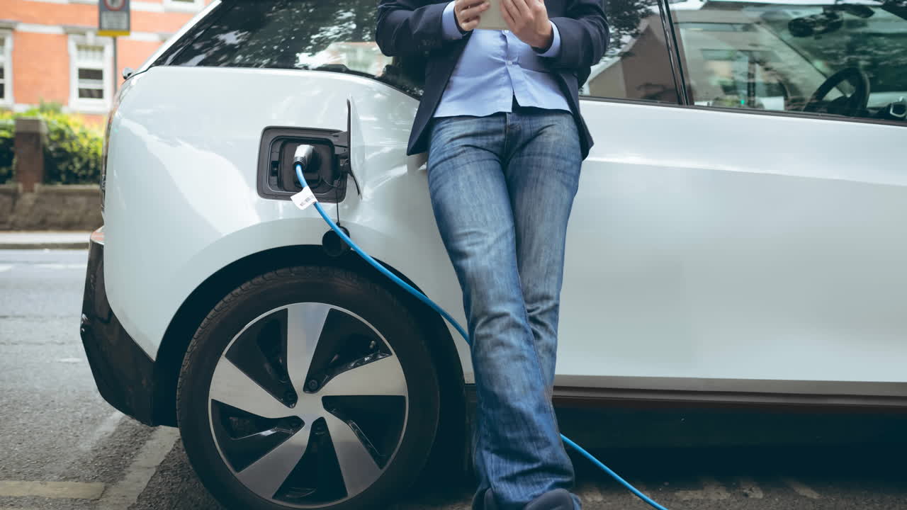 Sección media de hombre caucásico cargando coche eléctrico