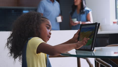 parents watching daughter using drawing app on digital tablet at home