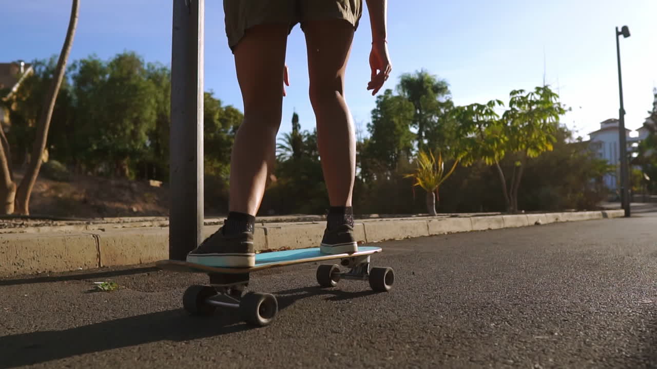 con una sonrisa alegre, una mujer monta su patineta al atardecer a lo largo del camino del parque flanqueado por palmeras y terreno arenoso. una imagen de personas felices que viven una vida saludable