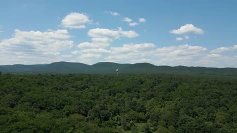 Establishing shot of a water tower sphere in the middle of the forest - drone drifting away from the Hills of B&ouml;rzs&ouml;ny in the background - Hungary