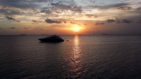 aerial view of a modern live aboard dive ship moored at sunset in dhangethi lagoon with a sea plane passing