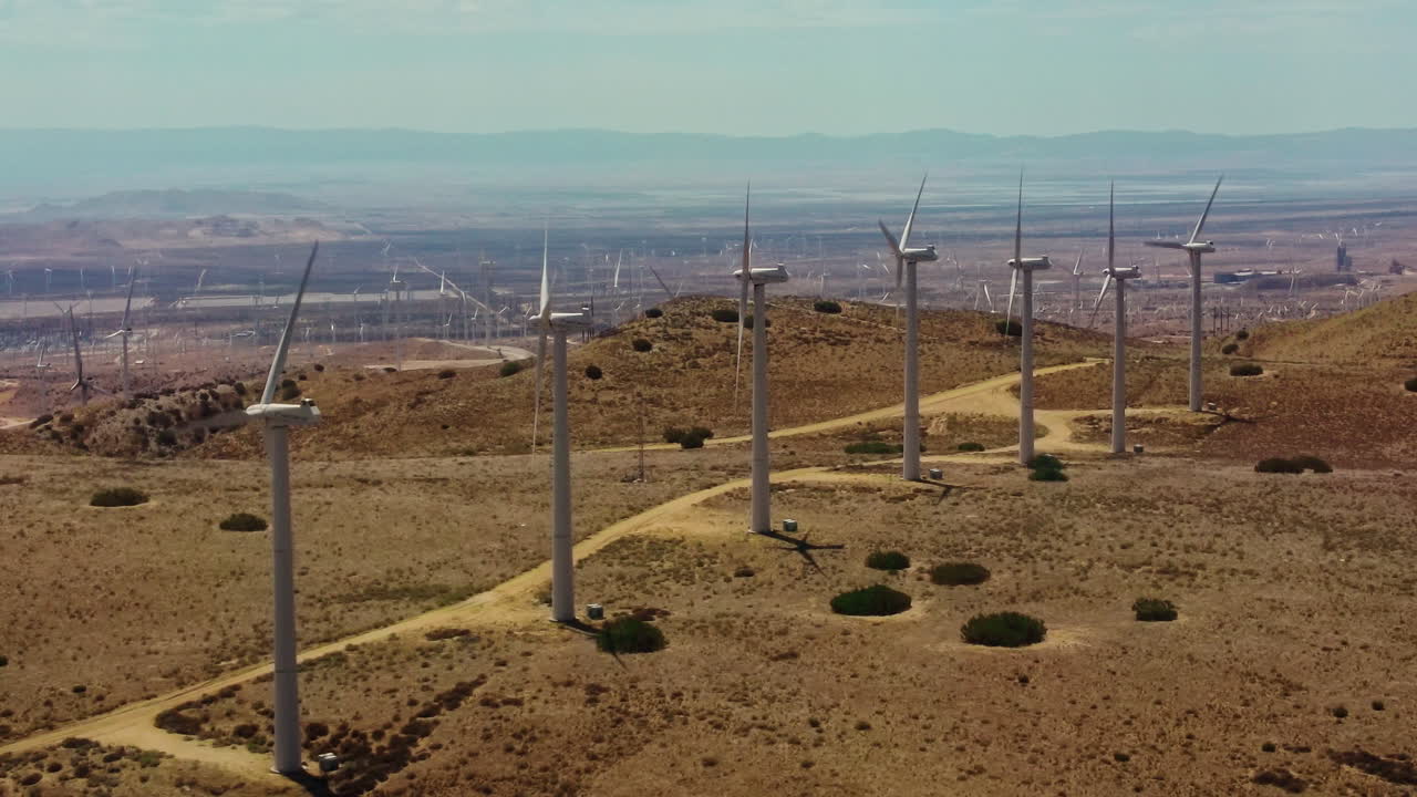 서비스 경로로 연결된 언덕 꼭대기의 끝없는 풍력 발전 단지의 인상적인 전망