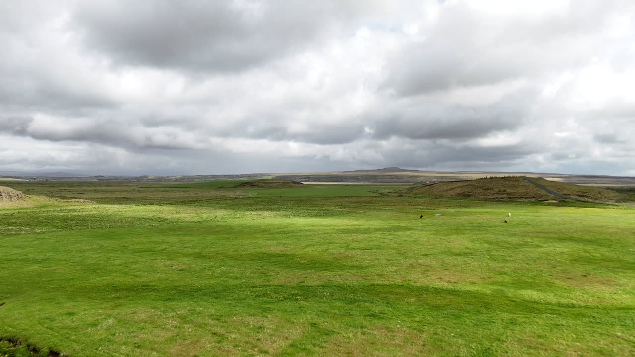 Luftdrone-visning af Islands Ringvej 1 i Suðurland, der krydser brede grønne marker under en lys, skyet himmel, og viser den berømte Ringvej gennem åbne sydlige landskaber
