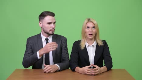young businesswoman making funny faces to young businessman