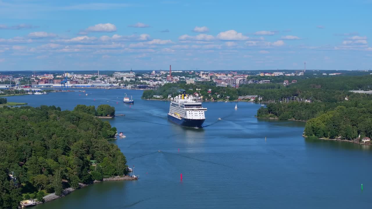 SAGA Cruise ship SPIRIT OF ADVENTURE navigating narrow archipelago fairway in Finland on departure. Aerial front view revealing limited space on both sides.