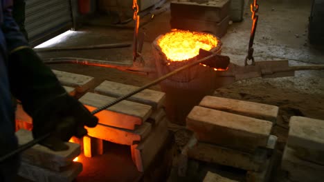 male workers carrying container of molted metal at workshop 4k