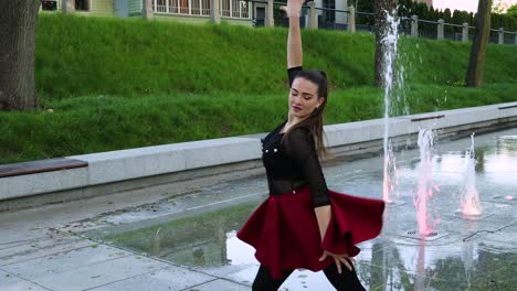 female dancer spins and turns next to a fountain in the park