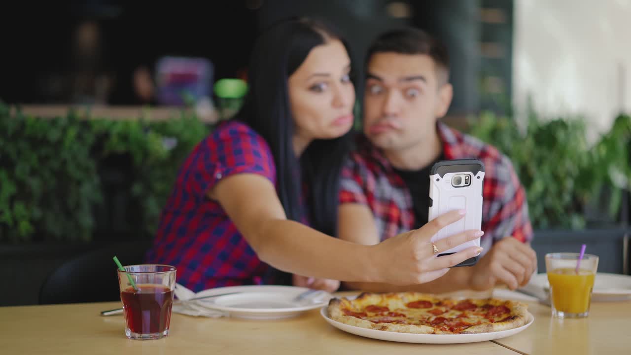 couple in love are making funny faces on the phone in the pizzeria on the background of the interior. Selfie