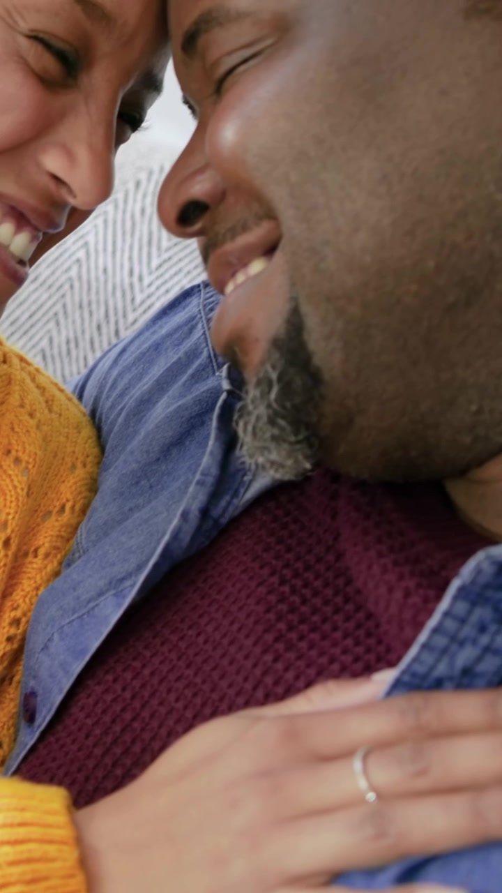 Video verticale: Donna con maglia gialla che tocca il petto di un uomo con cappello di Babbo Natale, lui si appoggia sorridendo gioiosamente sul divano.
