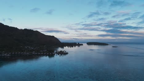luxury overwater bungalows at sunrise on moorea island, french polynesia. wide drone shot